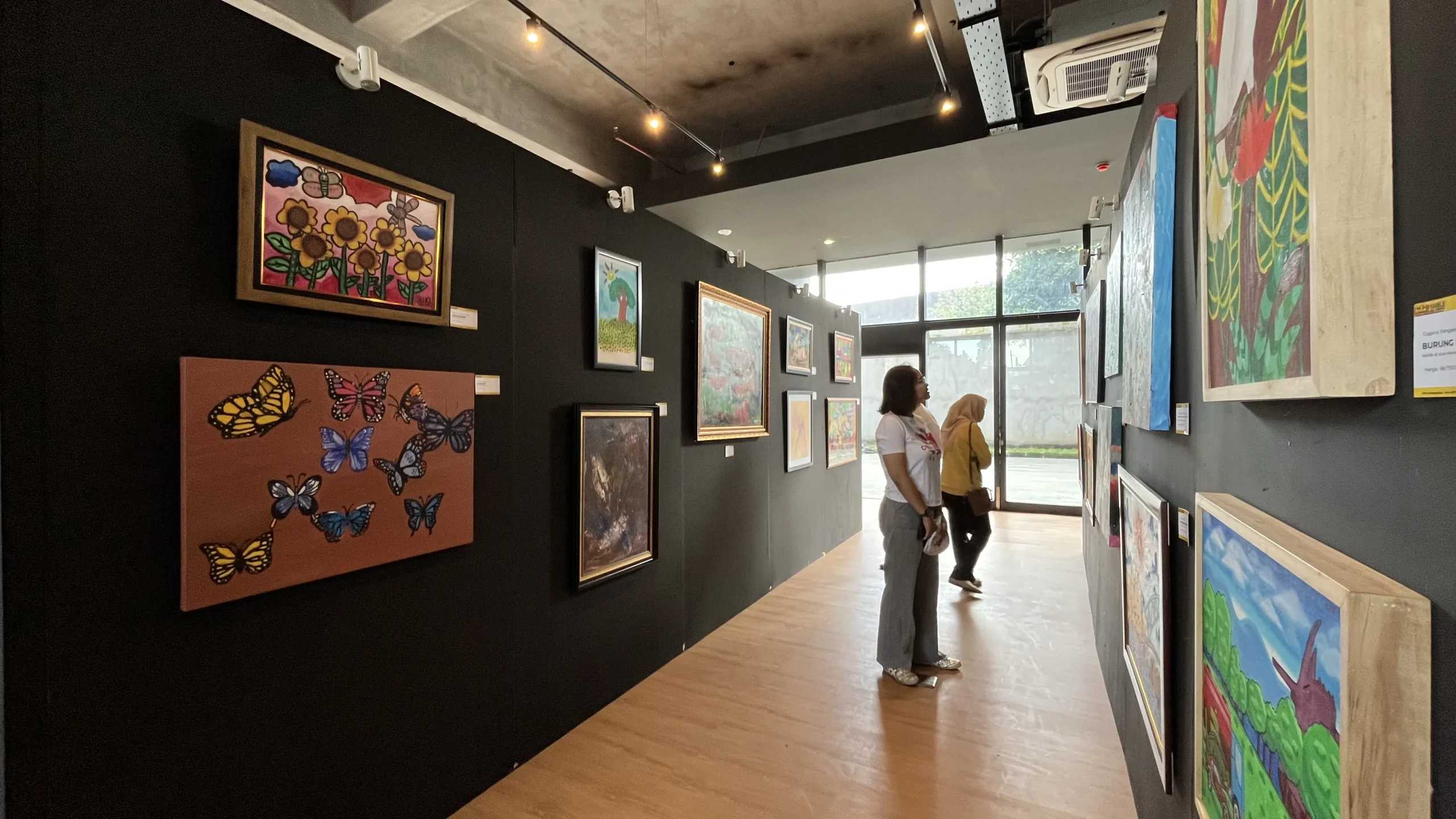 Pengunjung dan seniman berdialog di tengah keramaian pengunjung pameran seni autistik di GIK UGM, merayakan keberagaman ekspresi.