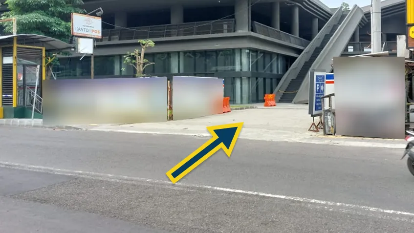 Tampak jalur masuk ke parkiran GIK UGM dari arah selatan Jalan Persatuan, terlihat papan penunjuk parkir dan kantor pos di sisi kiri.