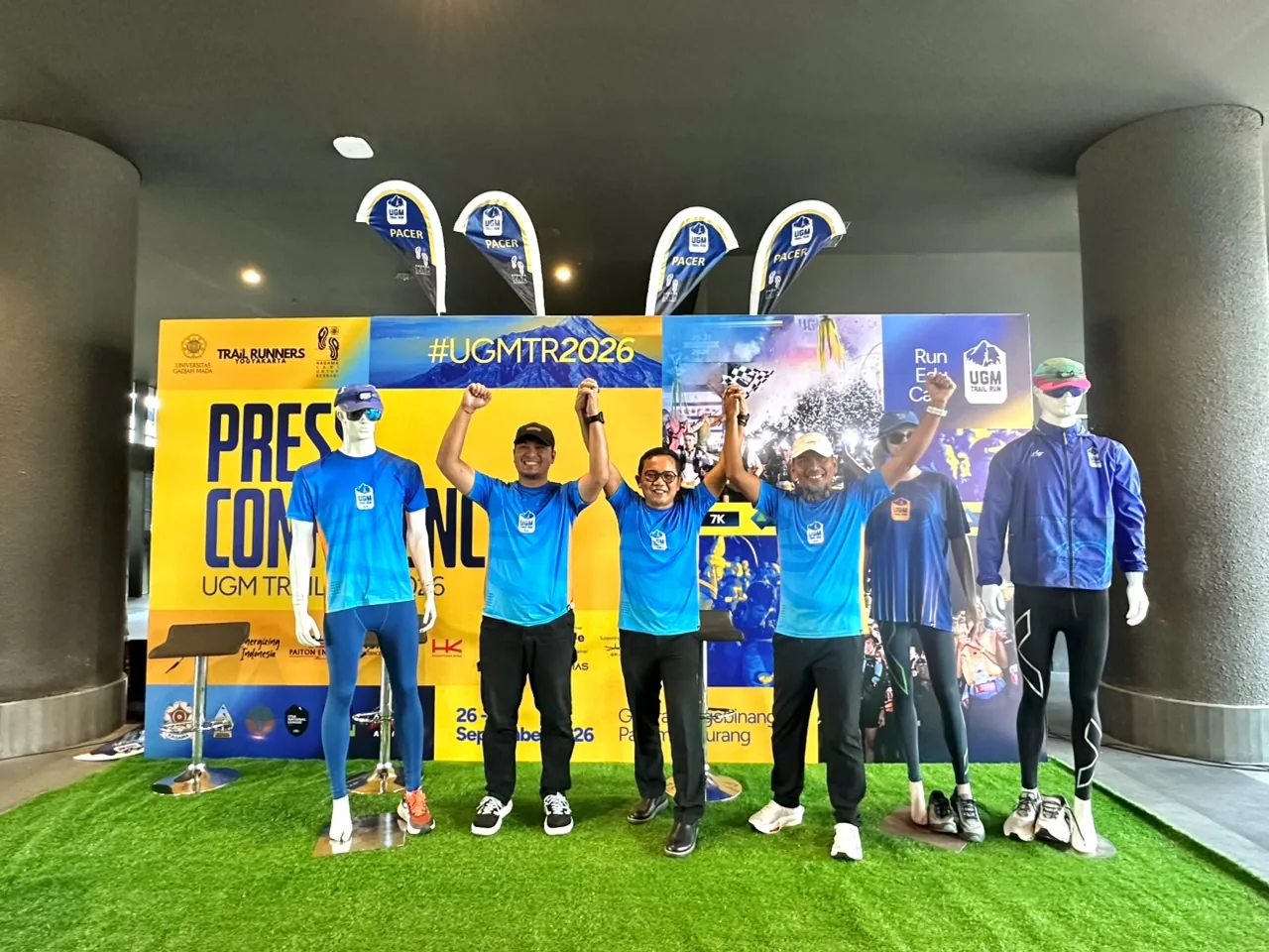 Tiga pembicara konferensi pers event trail run Jogja 2026, UGM Trail Run, mengangkat tangan di depan backdrop